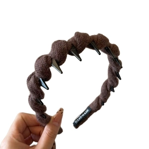 Brown wool-wrapped headband with non-slip teeth and handmade label on white background