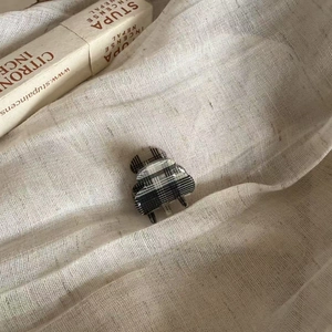 British style black and white plaid hair claw clip on neutral linen fabric background