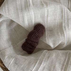 Gros plan d'une barrette en laine marron tricotée sur lin avec texture panier tressé