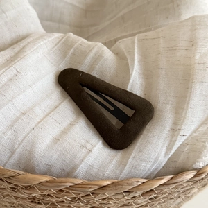 Detail of dark brown suede Fair Isle style BB hair clip on textured beige fabric