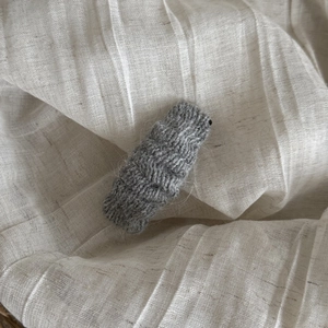 Gros plan d'une pince à cheveux en laine tricotée grise avec texture à vagues rétro