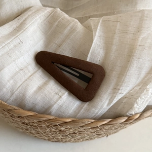 Minimalist chocolate brown suede triangle snap hair clip on a soft textured fabric