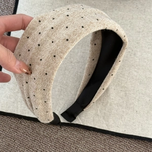 Detailansicht des beigen gepunkteten Strick-Stirnbands mit schwarzer rutschfester Innenseite