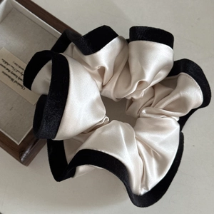 Detail of cream satin and black velvet scrunchie on a vintage wooden jewelry box