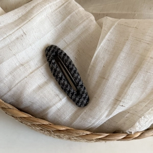 Close-up of Fair Isle checkered knit hair clip on textured fabric and woven basket