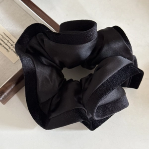 Elegant black satin hair scrunchie with velvet trim displayed on a minimalist wooden tray