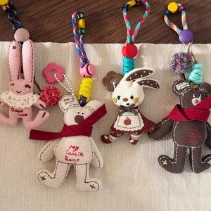 Detailed view of four plush charms featuring rabbits and bears with woven lanyards