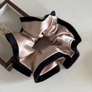 Detail of satin and black velvet hair scrunchie with soft sheen on wood tray