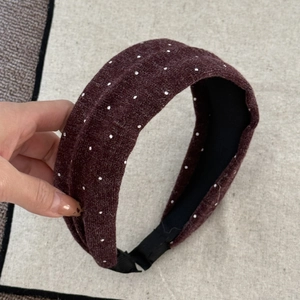 Nahaufnahme eines dunkelroten gepunkteten Stirnbands mit Strickstruktur und Innenfutter