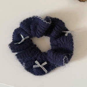 Détail d'un chouchou en maille bleu marine avec nœud argenté et texture mohair douce