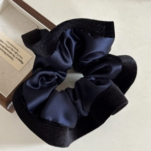Close-up of elegant dark blue satin scrunchie with a stylish black velvet trim