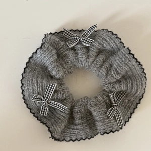 Détail du chouchou en tricot gris avec nœuds à carreaux noir et blanc et dentelle