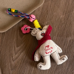 Detailed close-up of a My Cookie Bear plush keychain on a rustic wooden texture surface