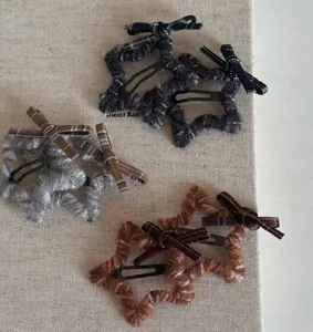 Detail of star-shaped plush hair clips with plaid bows and metal BB clip backing