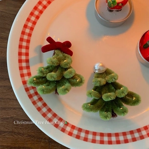 Detail view of handmade Christmas tree hair clips with green plush texture and festive decor