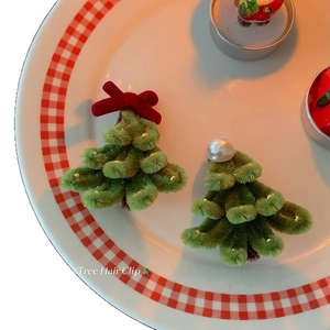 Close-up of handmade green plush Christmas tree hair clips with pearls and red velvet bows