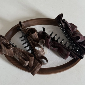 Detail of checkered bow banana clips in brown and dark red on a wooden tray