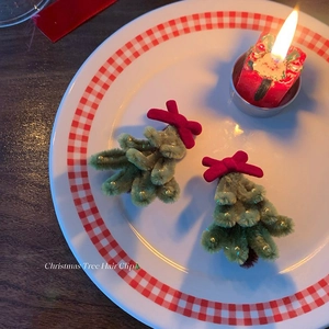 Detailed close-up of handmade green Christmas tree hair clips with red velvet bows on a plate