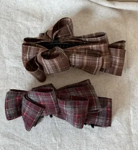 Close-up of brown and burgundy plaid fabric bow hair clips with retro British style