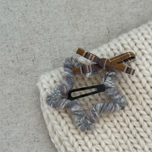 Star-shaped hair clip wrapped in grey and purple yarn with a brown plaid bow detail