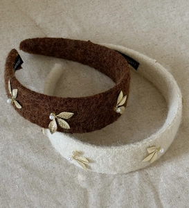 Detailed macro view of wool fabric headbands with golden leaf and pearl embellishments