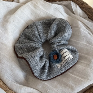 Gray knitted scrunchie with blue flower detail and stylish woven texture on fabric