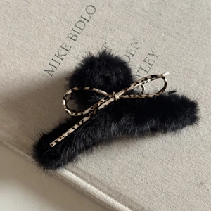 Vue détaillée d'une pince à cheveux en fausse fourrure noire avec nœud imprimé léopard