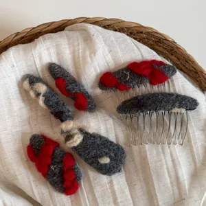 Détail de barrettes en laine feutrée à la main et peignes en métal gris et rouge