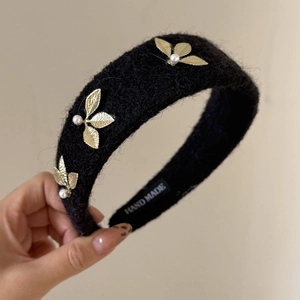 Detail of handmade wool headband with gold leaf accents and pearls for elegant hair styling