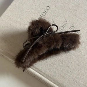 Vue détaillée de la grande pince à cheveux en peluche marron foncé avec nœud en cuir