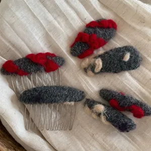 Barrettes et peignes à cheveux en feutre de laine gris, rouge et beige sur lin blanc