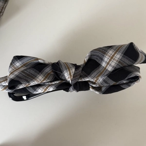 Vue détaillée du nœud en tissu à carreaux sur une pince à cheveux banane noire