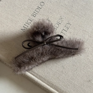 Grande pince à cheveux élégante en peluche marron café avec nœud sur un livre