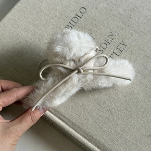 Détail de la pince à cheveux en fausse fourrure crème avec un nœud en cuir délicat