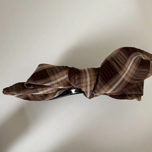 Vue détaillée d'une barrette noeud en tissu à carreaux café et kaki avec base noire