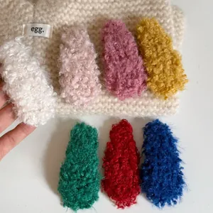 Close-up of soft lamb wool hair clips in seven colors on a creamy knit background