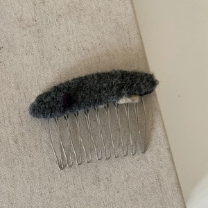 Vue détaillée du peigne à cheveux en feutre de laine gris avec des accents en peluche