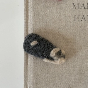 Gros plan d'une barrette en feutre faite main avec un mignon motif de patte gris et blanc