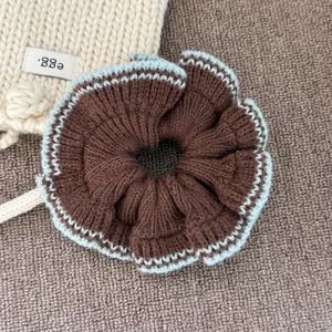 Détail du chouchou en maille marron avec bordure en crochet bleu clair contrastée