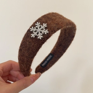 Détail du serre-tête en peluche marron avec flocon en strass et étiquette fait main