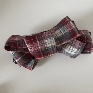 Macro shot of British plaid bow hair clip featuring red and white thick fabric texture