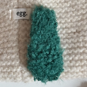 Plush faux lamb wool hair clip in dark green for women on knit background