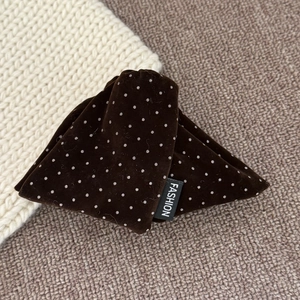 Detail of vintage velvet polka dot hair clip with a fashion label on woven texture