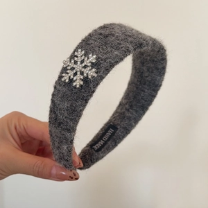 Détail du serre-tête en peluche grise avec flocon en strass et étiquette Handmade