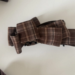 Macro shot of brown plaid fabric bow hair clip with vintage aesthetic and metal clasp