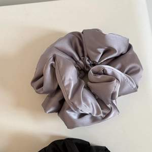 Close-up of soft dusty purple satin scrunchie with silky texture and voluminous pleats