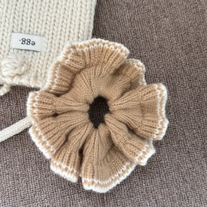 Gros plan d'un chouchou en tricot kaki avec bords en dentelle blanche et texture côtelée
