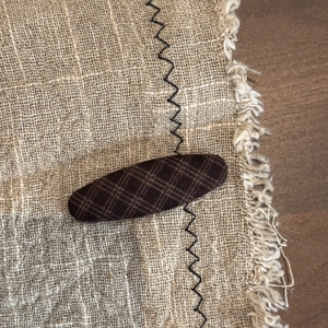Vintage brown plaid fabric hair clip with BB clip design on a neutral linen background