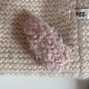 Close-up of a pink plush faux fur hair clip with soft texture on knitted fabric