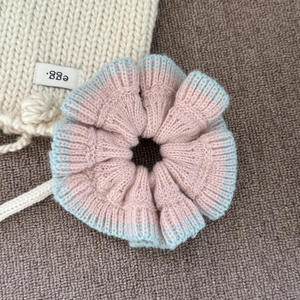 Détail d'un chouchou en tricot rayé rose et bleu clair avec bords ondulés doux